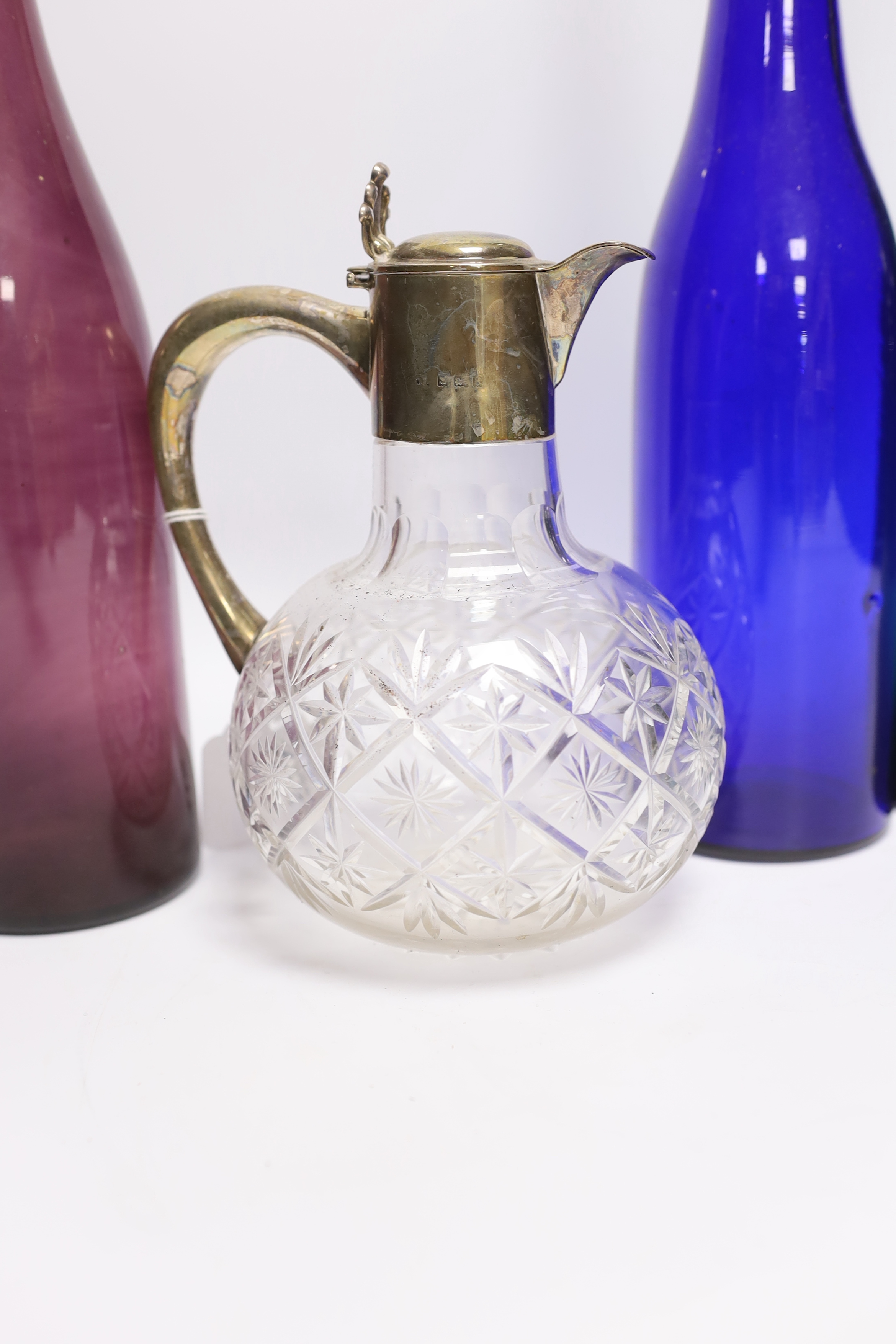 A silver mounted glass claret jug and three coloured glass bottles, 37cm